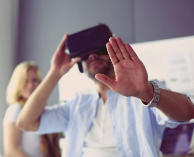 Genç erkek yazılım programcısı ofiste üç boyutlu sanal gerçeklik gözlükleriyle yeni bir uygulama test ediyor..