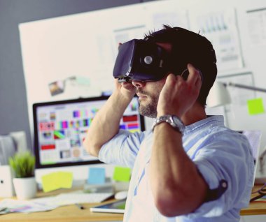 Genç erkek yazılım programcısı ofiste üç boyutlu sanal gerçeklik gözlükleriyle yeni bir uygulama test ediyor..