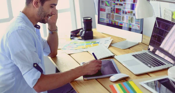 Porträt eines jungen Designers, der im Grafikstudio vor Laptop und Computer sitzt, während er online arbeitet. — Stockfoto