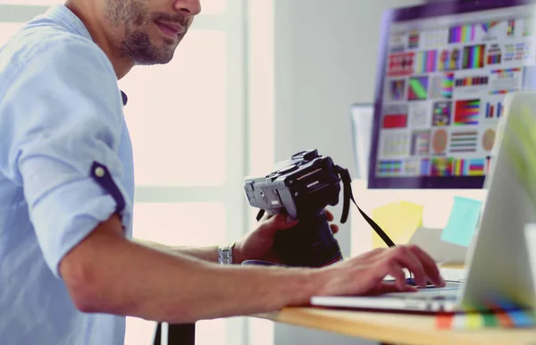 Portrait of young designer sitting at graphic studio in front of laptop and computer while working online.