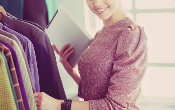 Mooie jonge stylist bij rek met hangers — Stockfoto