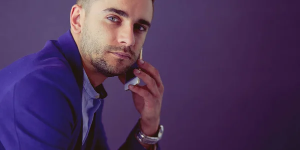 Joven empresario sentado aislado sobre fondo gris. —  Fotos de Stock