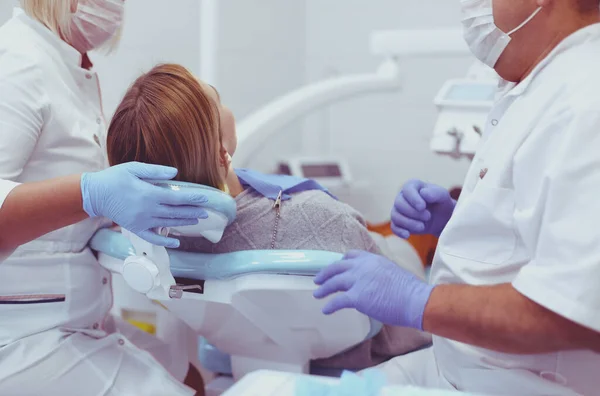 Starszy dentysta w gabinecie stomatologicznym rozmawia z pacjentką i przygotowuje się do leczenia — Zdjęcie stockowe