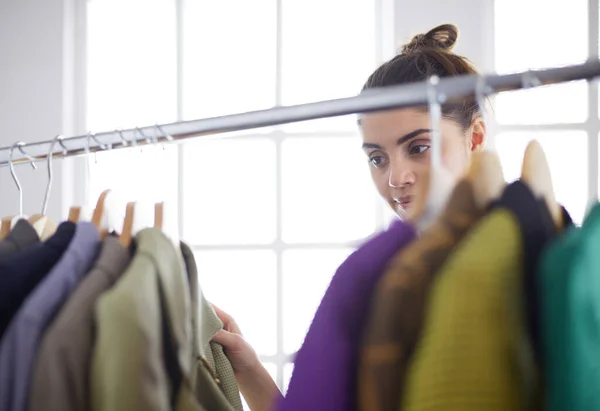 Mooie jonge stylist bij rek met hangers — Stockfoto