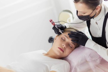 Güzellik salonunda kaş makyajı yapılan genç bir kadın.