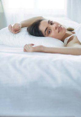 Güzel bir kadın yatağında uzanıyor.