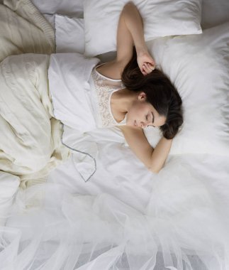 Güzel bir kadın yatağında uzanıyor.