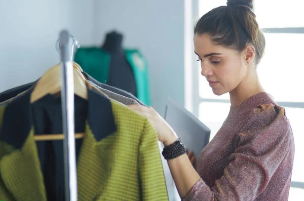 Beautiful young stylist near rack with hangers — Stock Photo, Image