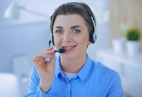 Ernstige mooie jonge vrouw die werkt als support telefoon operator met headset in het kantoor — Stockfoto