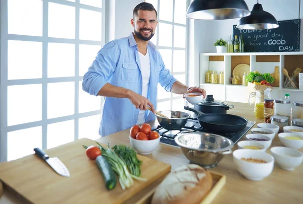 Чоловік слідує рецепту на цифровому планшеті і готує смачну і здорову їжу на кухні вдома — стокове фото