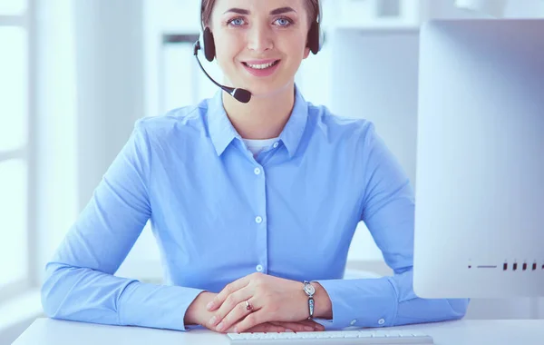 Серьёзная красивая молодая женщина работает оператором сотовой связи с гарнитурой в офисе — стоковое фото