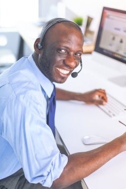 Kulaklıklı Afro-Amerikan işadamı laptopuyla çalışıyor.