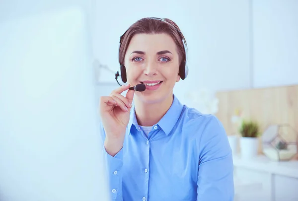 Mujer bastante joven y seria que trabaja como operador de telefonía de apoyo con auriculares en la oficina — Foto de Stock
