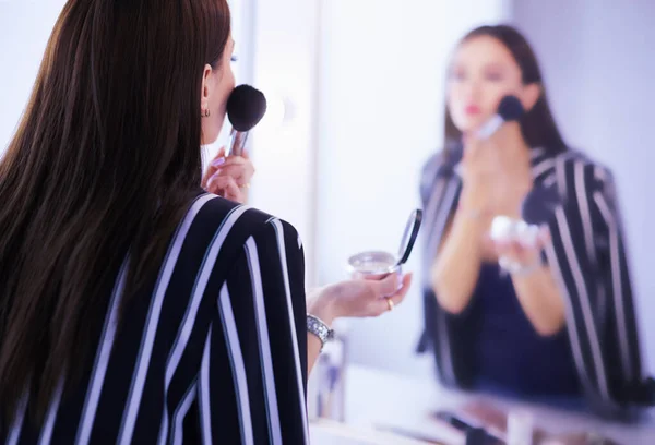 Schönheit Frau beim Schminken. schönes Mädchen, das in den Spiegel schaut und Kosmetik mit einem großen Pinsel anwendet — Stockfoto