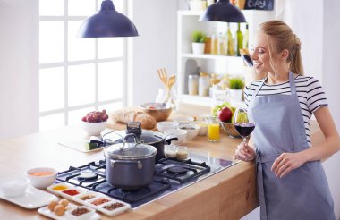 Güzel kadın mutfakta şarap içiyor.