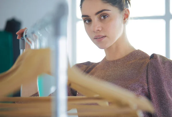 Mooie jonge stylist bij rek met hangers — Stockfoto