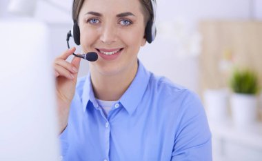 Ofisinde kulaklık takmış, telefon operatörü olarak çalışan ciddi ve güzel bir genç kadın.