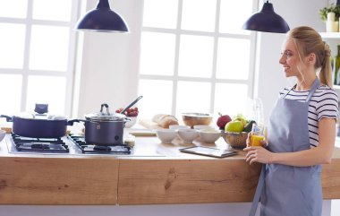 Çekici kadın mutfakta dikilirken elinde bir bardak portakal suyu tutuyor.