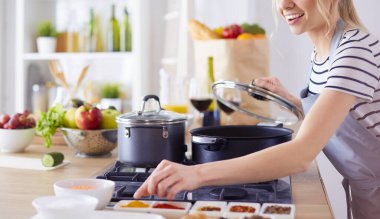 Evdeki mutfakta yemek pişiren güzel genç bir kadın.