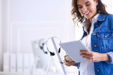 Gülümseyen kadın kahve içiyor ve kafede tablet kullanıyor.
