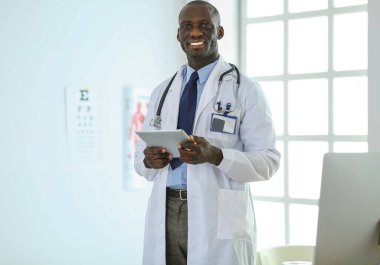 Tablet bilgisayarlı siyahi bir doktor hastanede bekliyor.