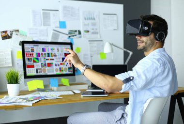 Genç erkek yazılım programcısı ofiste üç boyutlu sanal gerçeklik gözlükleriyle yeni bir uygulama test ediyor..