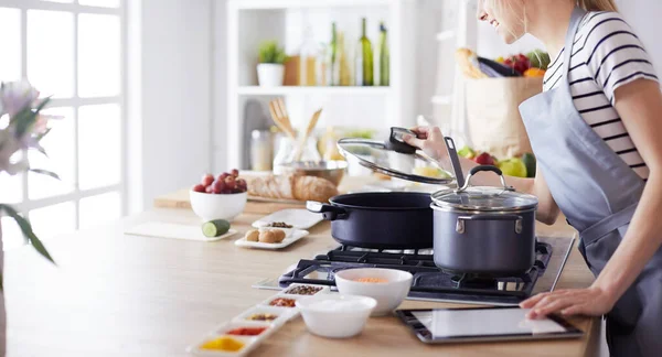 Jonge vrouw met behulp van een tablet computer om te koken in haar keuken — Stockfoto