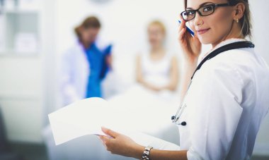 Genç bayan doktor hastanede steteskopla dikiliyor.
