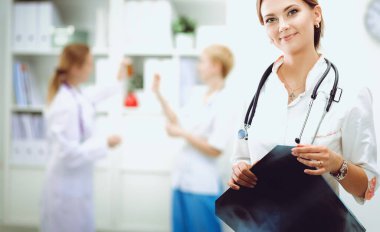 Genç bayan doktor hastanede steteskopla dikiliyor.