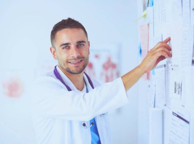 Genç ve kendinden emin erkek doktor portresi tıp ofisinde duruyor..