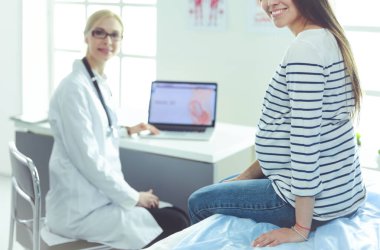 Hastanede doktorla gülümseyen güzel bir hamile kadın.