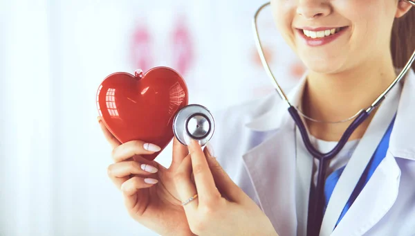 Ein Arzt mit Stethoskop untersucht rotes Herz, isoliert auf weißem Grund — Stockfoto