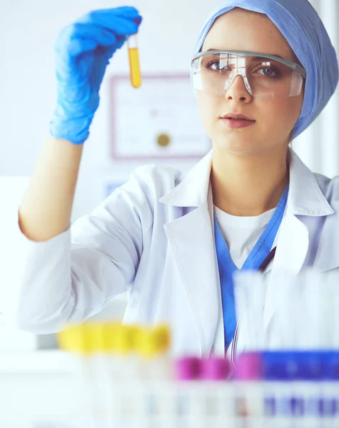 O femeie cercetătoare medicală sau științifică sau un medic care se uită la un tub de testare cu soluție clară într-un laborator — Fotografie, imagine de stoc