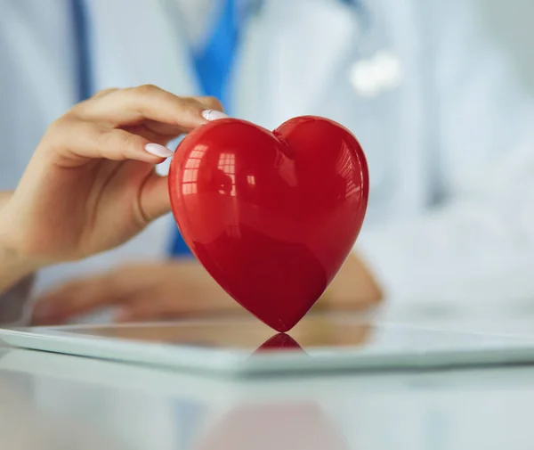 Médecin femme avec stéthoscope tenant le cœur, sur fond clair — Photo