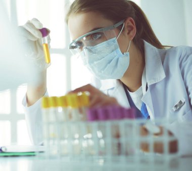 Modern laboratuvar veya hastanede plastik tıbbi tüplerle çalışan araştırmacı, doktor, bilim adamı veya laboratuvar asistanı
