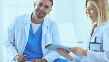 Yakışıklı doktor genç bayan doktorla konuşuyor ve ofisinde otururken notlar alıyor..