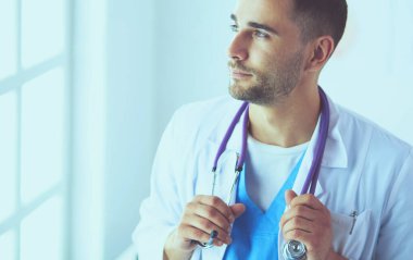 Genç ve kendinden emin erkek doktor portresi tıp ofisinde duruyor..