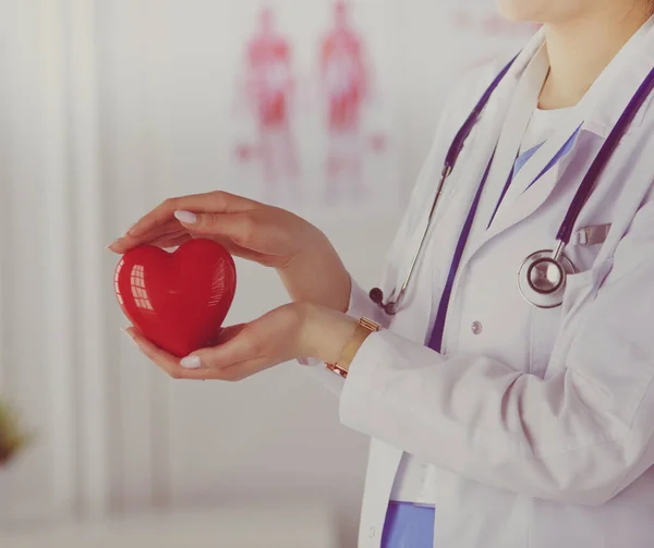 Cardiologista com coração vermelho e estetoscópio à mesa — Fotografia de Stock