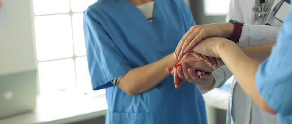 Artsen en verpleegkundigen in een medisch team stapelen handen — Stockfoto