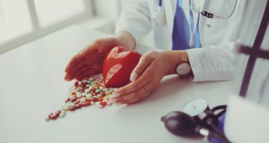 Masada kırmızı kalbi ve steteskopu olan kardiyolog.