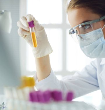 Kadın araştırmacı, beyaz şişeler ve şişelerle çevrili.