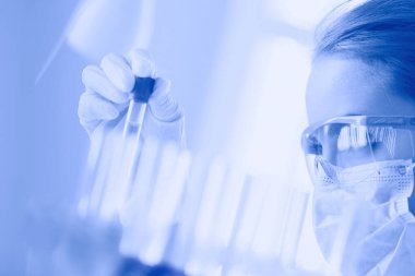 Laboratuvarda sıvı yeşil çözeltiye bakan bir tıbbi veya bilimsel araştırmacı ya da doktor