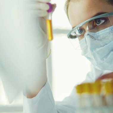 Hastanedeki kan örneğini analiz eden güzel bir kadın laboratuvar asistanı portresi.