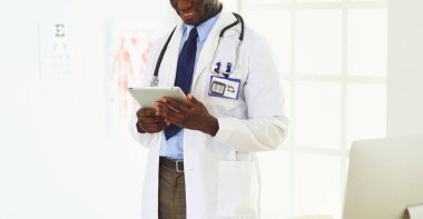 Tablet bilgisayarlı siyahi bir doktor hastanede bekliyor.
