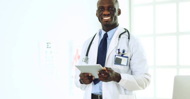 Tablet bilgisayarlı siyahi bir doktor hastanede bekliyor.