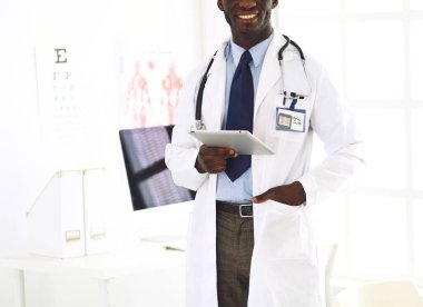 Tablet bilgisayarlı siyahi bir doktor hastanede bekliyor.