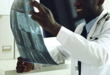 Genç Afrikalı doktor portresi hastaların röntgenlerini tutuyor.