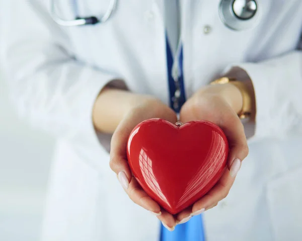 Doctora con estetoscopio sosteniendo el corazón, sobre fondo claro —  Fotos de Stock