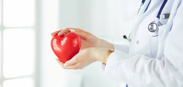 Female doctor with stethoscope holding heart, on light background — Stock Photo, Image