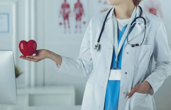 Médica com estetoscópio segurando coração, em fundo claro — Fotografia de Stock